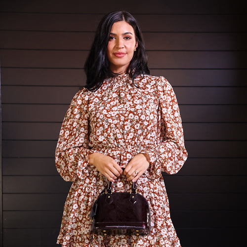 Woman wearing floral dress, holding handbag.